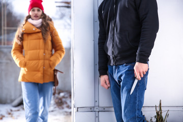 Male thief going to attack young woman outdoors