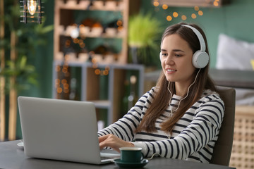 Young woman with laptop using wifi in cafe