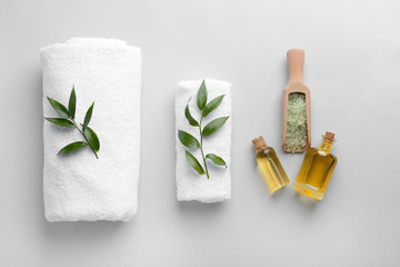 Spa composition with towels, sea salt and essential oil on light background