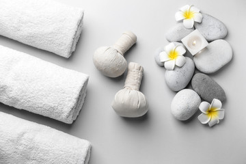 Fototapeta na wymiar Spa composition with herbal bags, towels and stones on light background