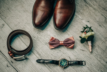leather shoes, bow tie, leather belt, flower boutonniere, watches lie on an isolated background