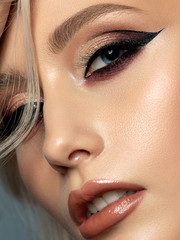 Portrait of young beautiful woman with evening make up. Modern fashion eyeliner wing. Studio shot....