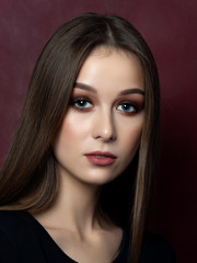 Naklejka premium Portrait of young beautiful woman over dark wine red background. Studio shot