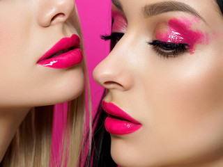 Closeup portrait of two young beautiful women with fashion pink makeup. Bright pink lip gloss and...