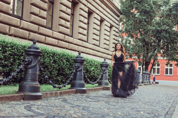 Fashionable close up street portrait of brunette beautiful girl walking in old town of Riga. Beauty, fashion concept
