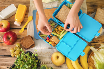Mother preparing lunch for schoolchild at table