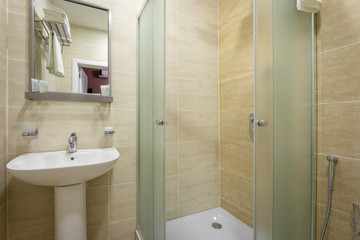 Bathroom,tiles and bright colors of broom, shower with frosted doors,mirror above the sink. Hanging...