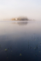 Foggy autumnal morning by the lake. Natural sunrise light. Trondheim area in Norway.
