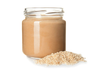 Jar of tasty tahini with sesame seeds on white background