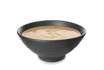 Bowl of tasty tahini on white background
