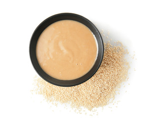 Bowl of tasty tahini with sesame seeds on white background