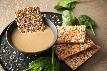 Bowl of tasty tahini with crackers on table