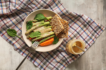 Plate with tasty tahini, fresh vegetables and crackers on table