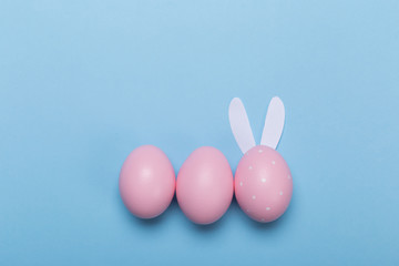 pink easter eggs in nest on pastel color background with space.