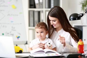 Young mother with her son working in office