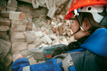 Destroying gender stereotypes. Woman wearing helmet using different male work tools. Gender...