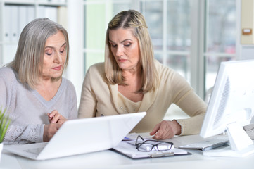 two excited mature women working in office