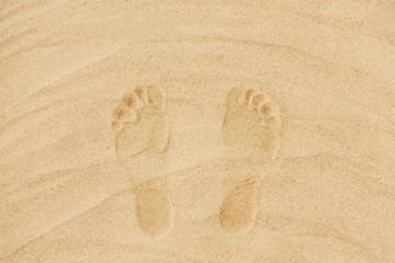summer vacation concept - footprints in sand on beach