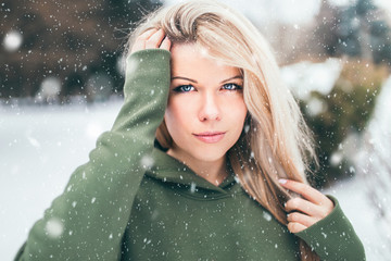 Beautiful young woman with healthy skin - outdoor portrait in winter in snowfall - snow flakes...