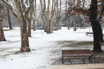 Fototapeta na wymiar bench with snow in a cold day in a city park