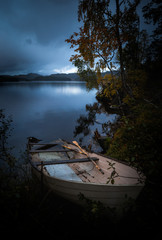 Wooden boat by the lake shore, Norway, beautiful autumn time, calm water.