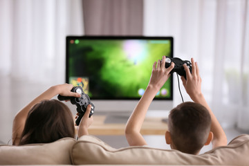 Cute little children playing computer game at home