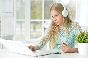 little girl with headphones and laptop at home