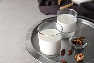 Glasses of fresh milk with nuts on tray