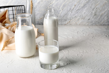 Glass and bottles of fresh milk on light table