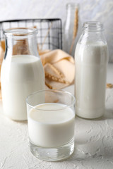 Obraz na płótnie Canvas Glass and bottles of fresh milk on light table
