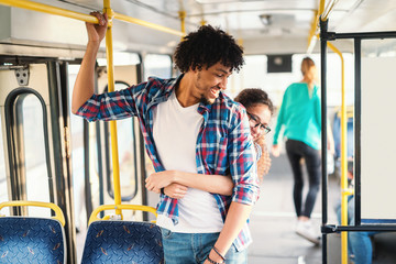 Young multicultural couple hugging in the public transport.