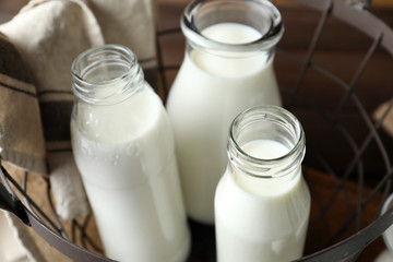 Basket with bottles of fresh tasty milk on table
