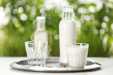 Glass and bottle of fresh milk on table outdoors