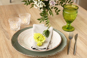 Beautiful festive table setting with floral decor on wooden background