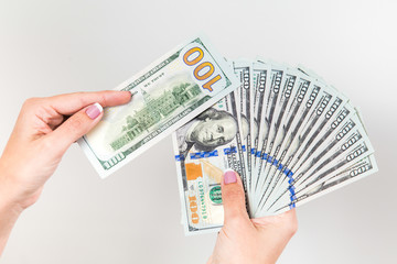 Closeup up view of white female hands holding many 100 dollars paper bills isolated on white background. Horizontal color photography.