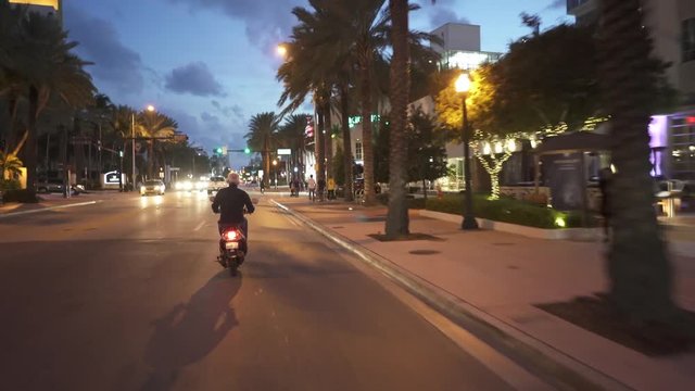 Following man riding scooter in Miamy beach at dusk