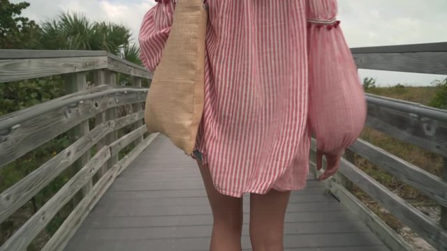 Dreamy boho chic woman walking towards beach on wild rustic path