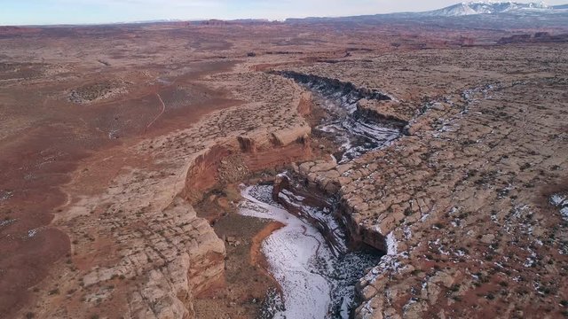 Aerial view flying over canyon cutting through the landscape in Utah near Arches National Park.