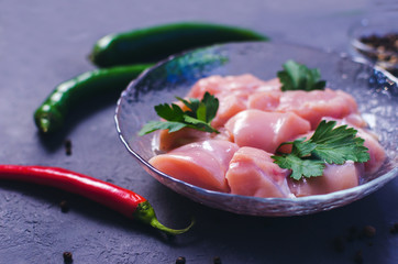Raw chicken cubes in bowl on dark stone table. Breast cubes.  Copy space. Selective focus.