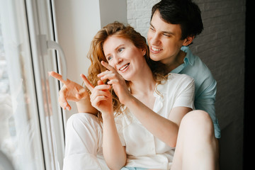 Happy girl and man hugging near window in home. 