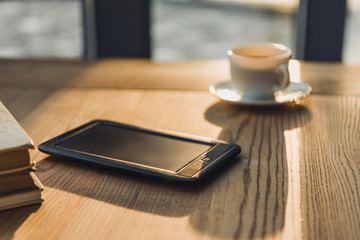 selective focus of e-book lying near cup with drink