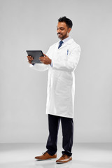 medicine, science and profession concept - smiling indian male doctor or scientist in white coat with tablet computer over grey background