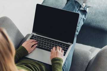 cropped view of woman using laptop with blank screen