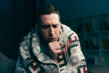 handsome man coughing while having flu at home