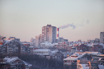 Fototapeta na wymiar Smoking from industrial chimneys of heating plant emits smoke, smog at sunset in city, pollutants enter atmosphere. Environmental disaster. Harmful emissions, exhaust gases into air. Heating season.