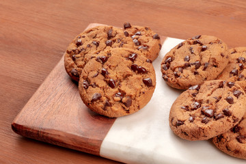 Freshly baked golden brown chocolate chip cookies on a dark rustic wooden background with copy space
