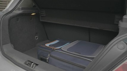 Teen man preparing his trip removing luggage from trunk and stacking them again bringing order and space