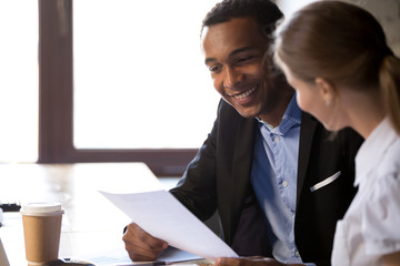 Excited black employer read applicant resume at interview