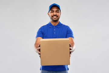 mail service and shipment concept - happy indian delivery man with parcel box in blue uniform over...