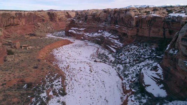 Flying backwards through canyon in the Utah desert past cliffs and over slackline stretched across the canyon near Moab.